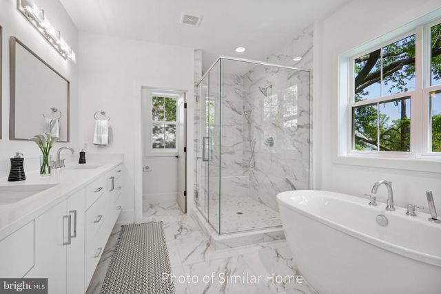 a spacious bathroom with a double vanity sink a large mirror a shower and a bathtub