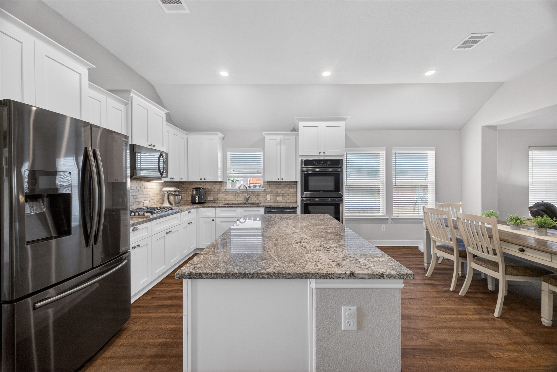1009 Bright Star Cove Georgetown, TX 78628 - Photo 5 of 40 a kitchen with stainless steel appliances granite countertop a refrigerator a stove a sink a dining table and chairs
