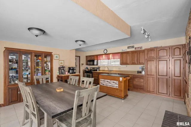 a kitchen with granite countertop a stove a sink dishwasher a dining table and chairs with wooden floor