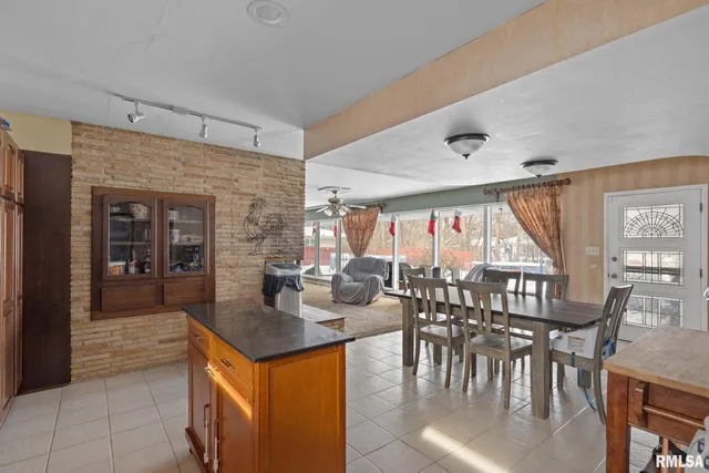 a dining hall with stainless steel appliances granite countertop a table chairs and a view of living room