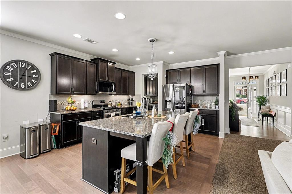 7284 Demeter Atlanta, GA 30349 - Photo 5 of 33 a kitchen with stainless steel appliances granite countertop a stove top oven a sink a stove a dining table and chairs with wooden floor