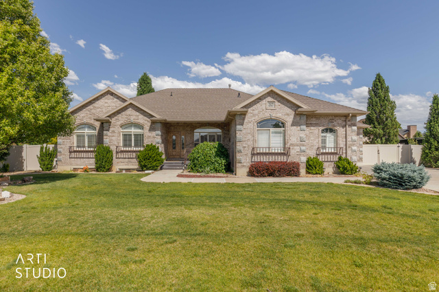 2327 Bluff Ridge Drive Syracuse, UT 84075 - Photo 4 of 66 Stone veneer exterior with multiple arched windows, prominent gables, a dark shingle roof, and a maturely landscaped front yard with a paved driveway