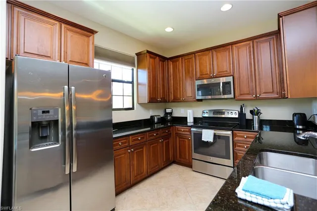 a kitchen with stainless steel appliances granite countertop a refrigerator a stove a sink and a microwave