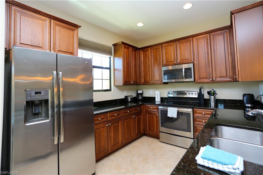 9082 Capistrano Street North, Unit 484 Naples, FL 34113 - Photo 12 of 35 a kitchen with stainless steel appliances granite countertop a refrigerator a stove a sink and a microwave