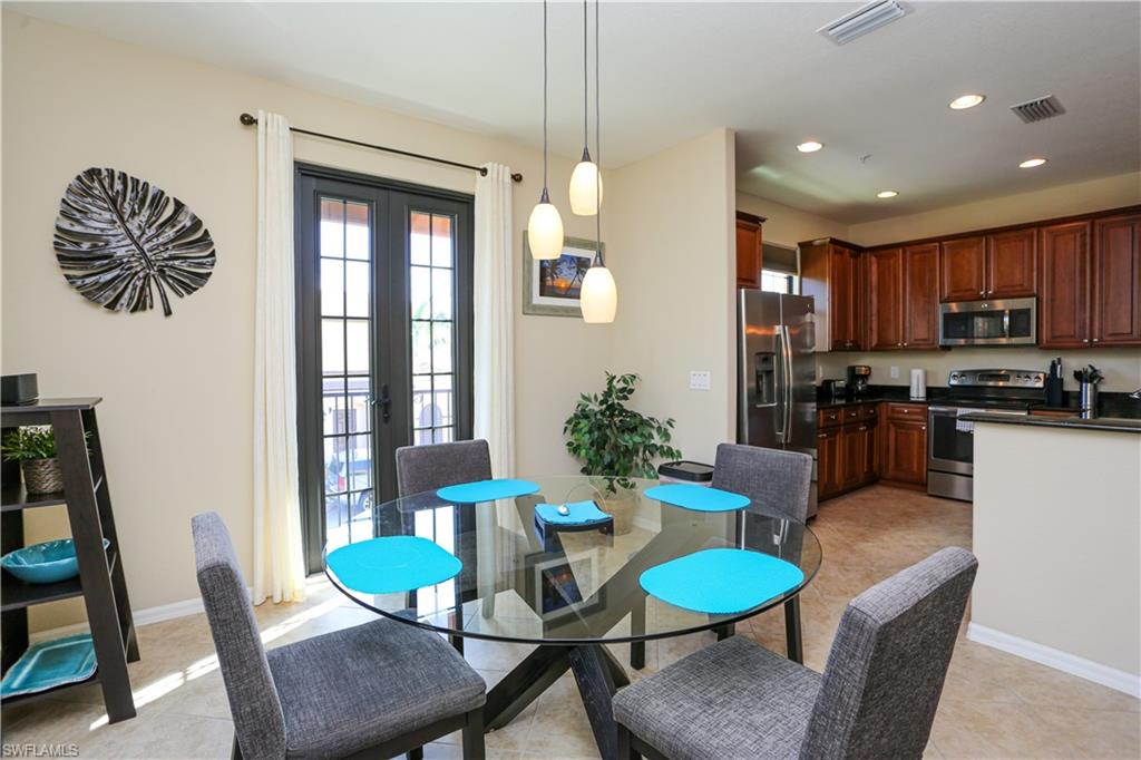 9082 Capistrano Street North, Unit 484 Naples, FL 34113 - Photo 15 of 35 a kitchen with stainless steel appliances kitchen island granite countertop a dining table chairs and a refrigerator