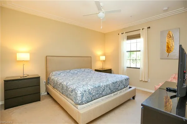 a bedroom with a bed and a flat tv screen on dresser