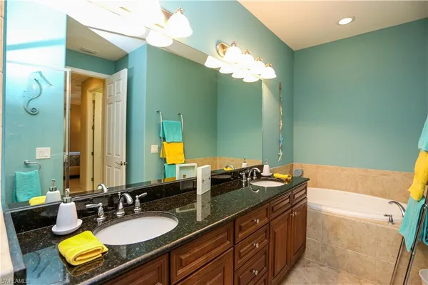 a bathroom with a granite countertop sink a mirror and a bathtub