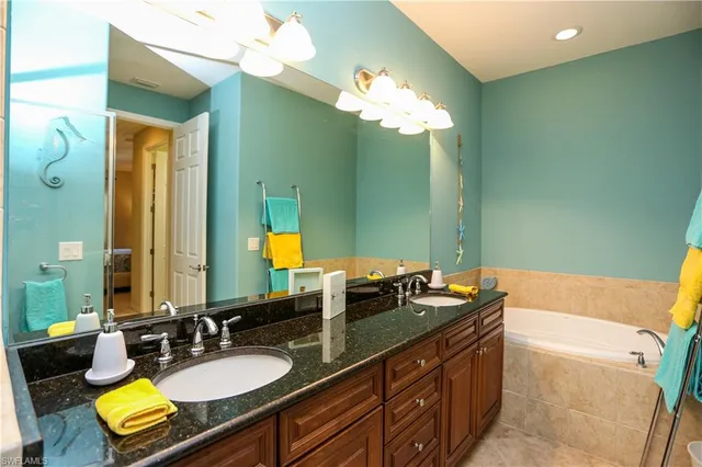 a bathroom with a granite countertop sink a mirror and a bathtub