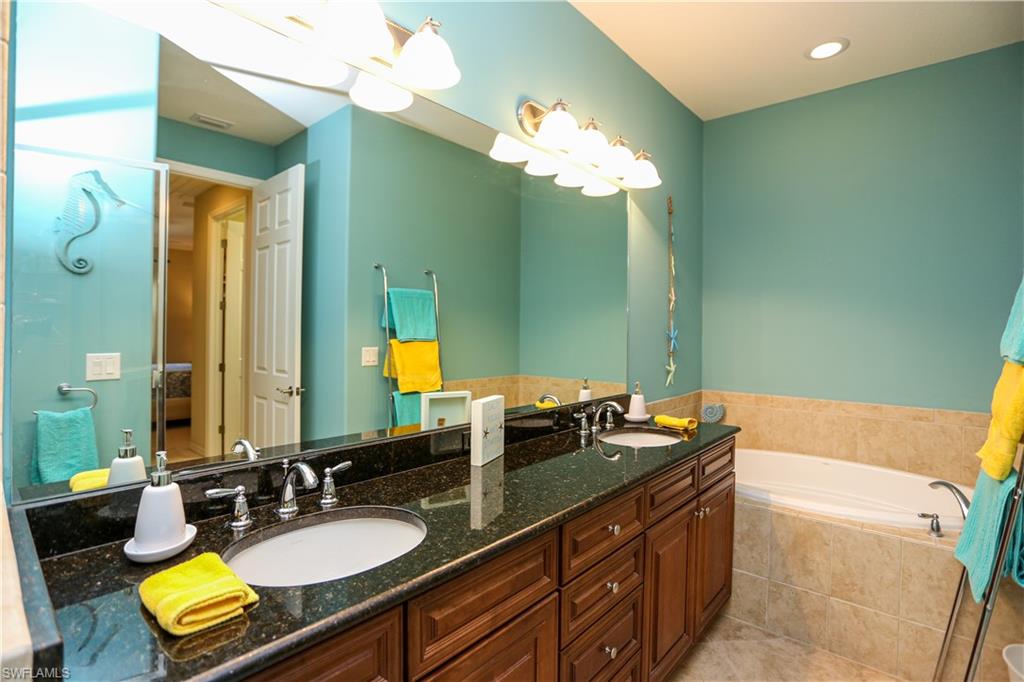 9082 Capistrano Street North, Unit 484 Naples, FL 34113 - Photo 19 of 35 a bathroom with a granite countertop sink a mirror and a bathtub