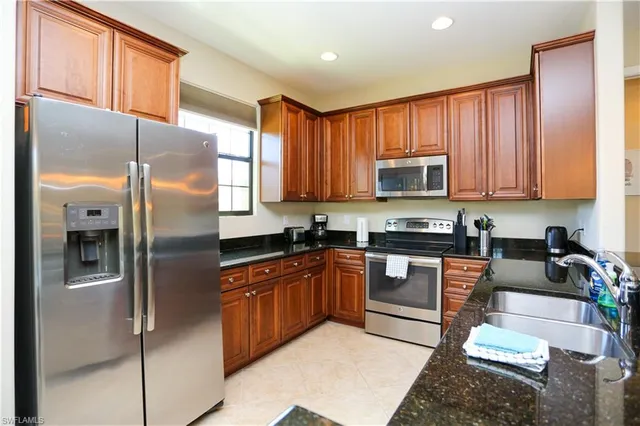a kitchen with stainless steel appliances granite countertop a refrigerator a stove top oven a sink and dishwasher