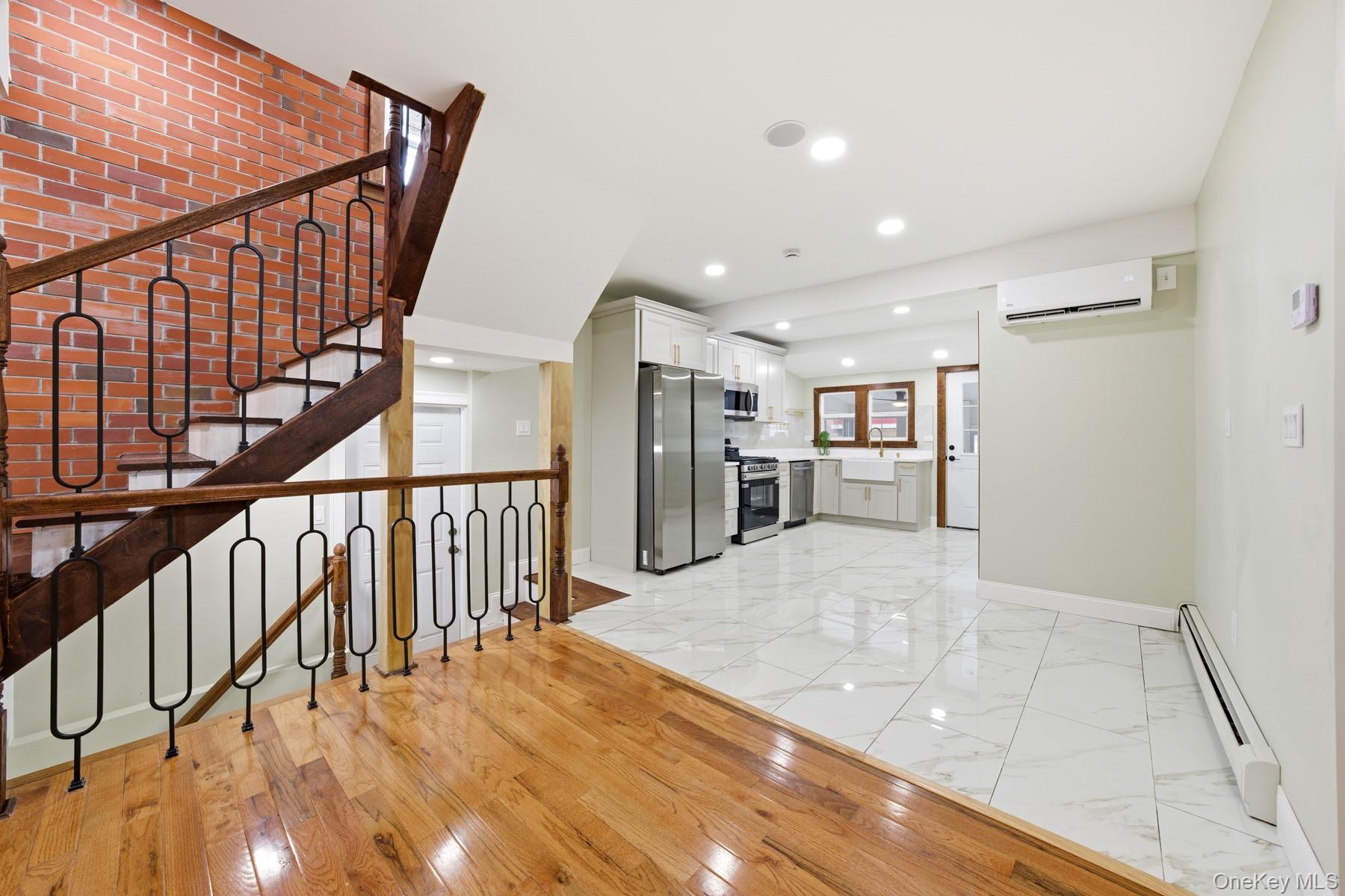 104-11 205th Street Queens, NY 11412 - Photo 11 of 50 Unfurnished living room featuring a baseboard heating unit, recessed lighting, light marble finish floors, stairs, and an AC wall unit