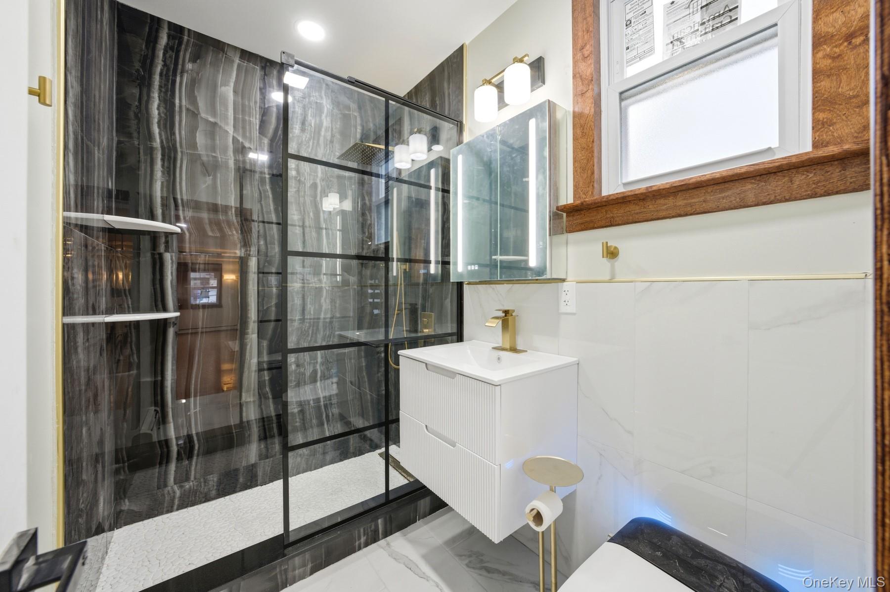 104-11 205th Street Queens, NY 11412 - Photo 12 of 50 Bathroom featuring a stall shower, vanity, marble finish floors, and tile walls