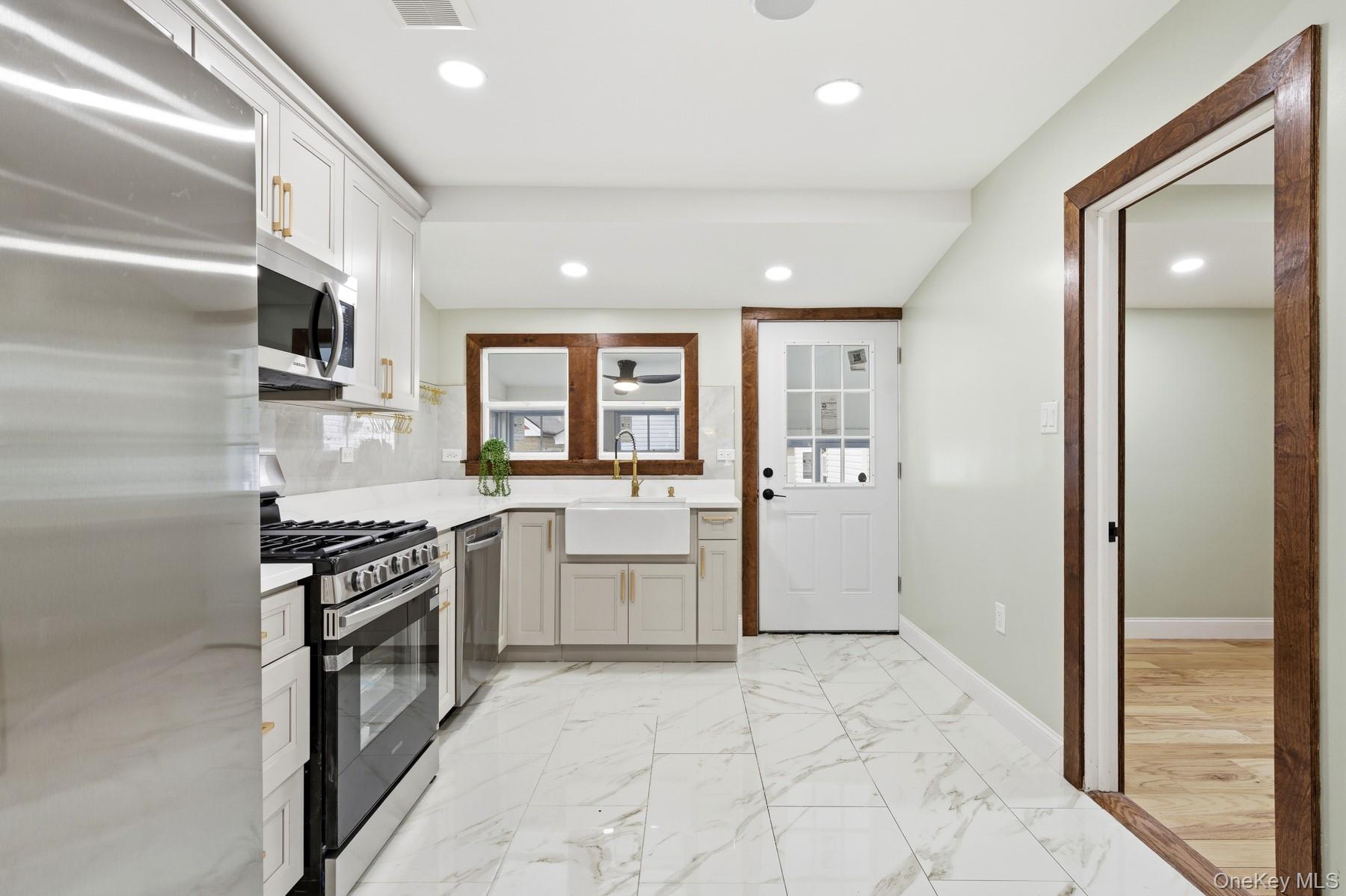 104-11 205th Street Queens, NY 11412 - Photo 13 of 50 Kitchen with stainless steel appliances, light marble finish flooring, recessed lighting, tasteful backsplash, and light stone countertops