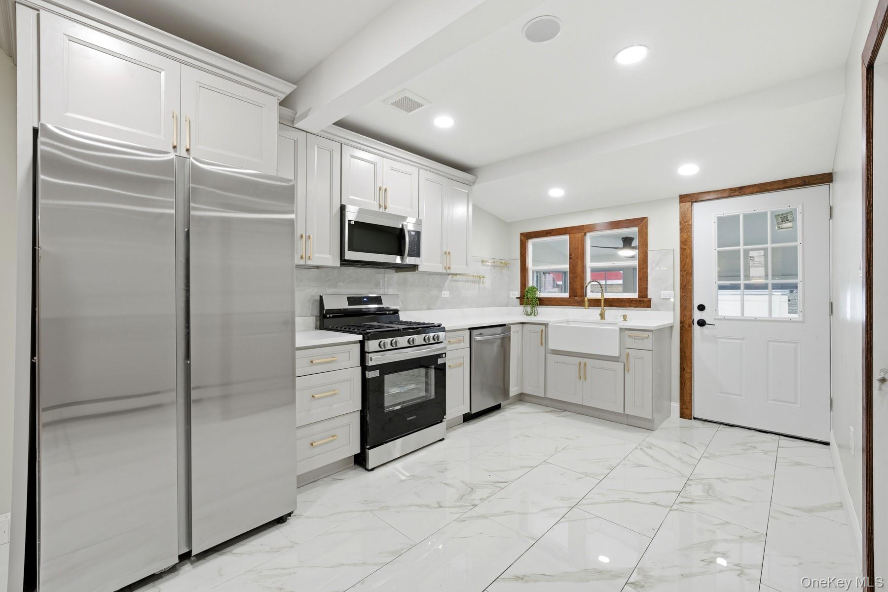104-11 205th Street Queens, NY 11412 - Photo 15 of 50 Kitchen with stainless steel appliances, tasteful backsplash, light marble finish flooring, recessed lighting, and white cabinets