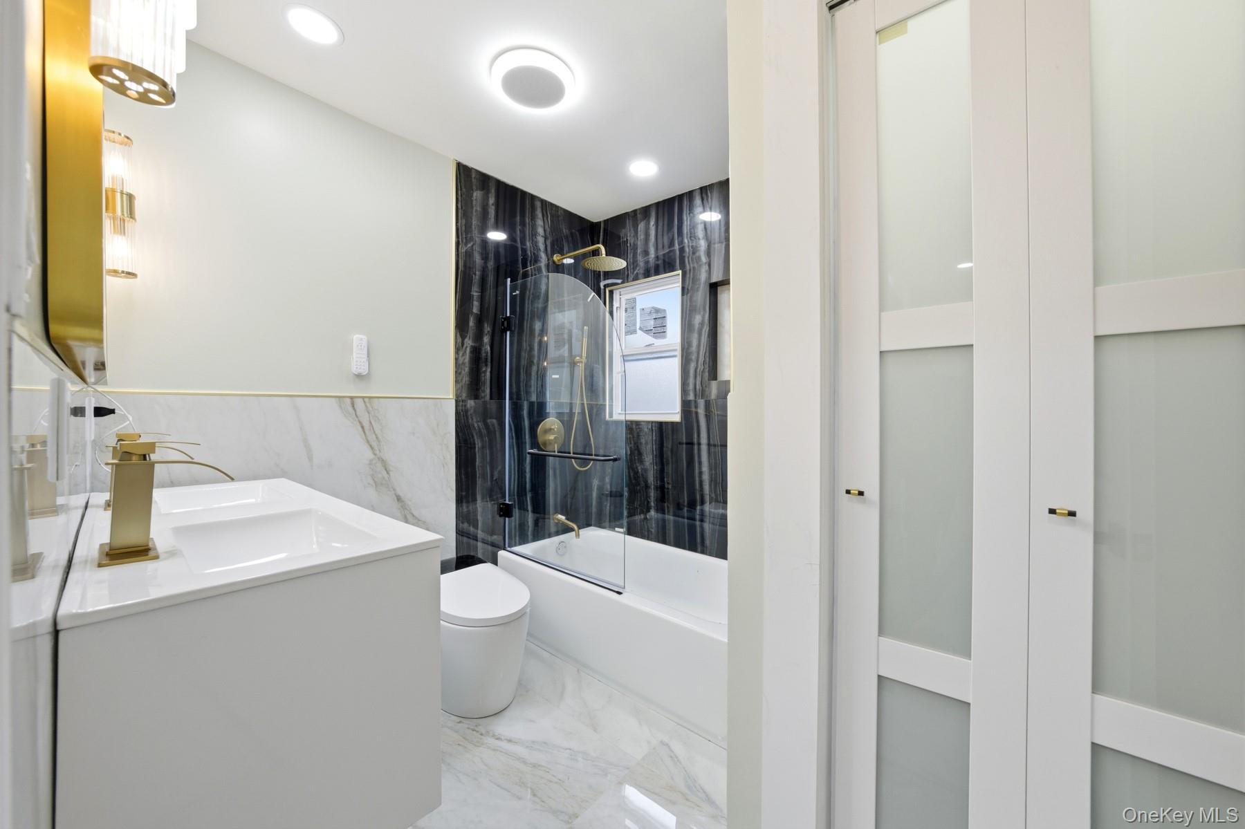 104-11 205th Street Queens, NY 11412 - Photo 23 of 50 Full bathroom with light marble finish floors, vanity, enclosed tub / shower combo, tile walls, and recessed lighting