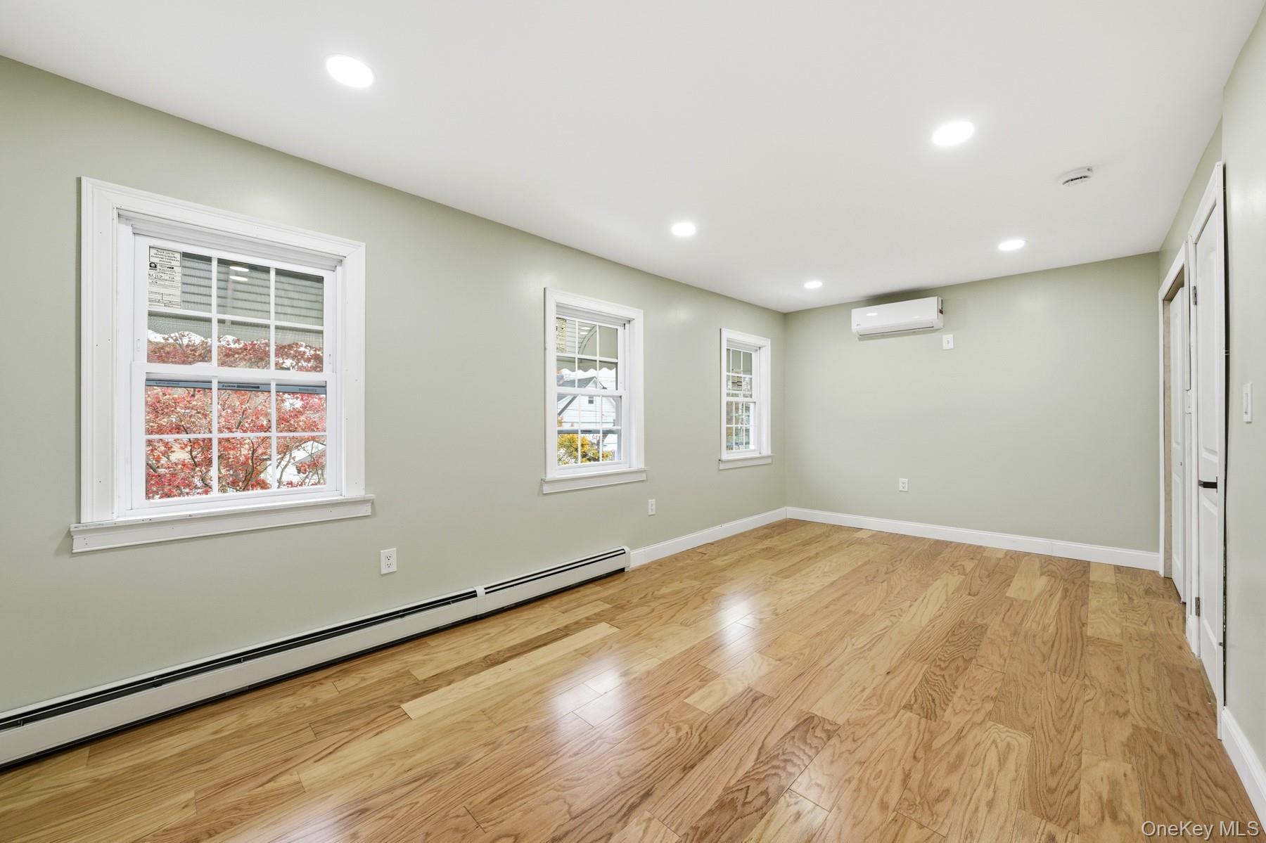 104-11 205th Street Queens, NY 11412 - Photo 31 of 50 Unfurnished room with a baseboard heating unit, light wood-style flooring, recessed lighting, and a wall mounted air conditioner