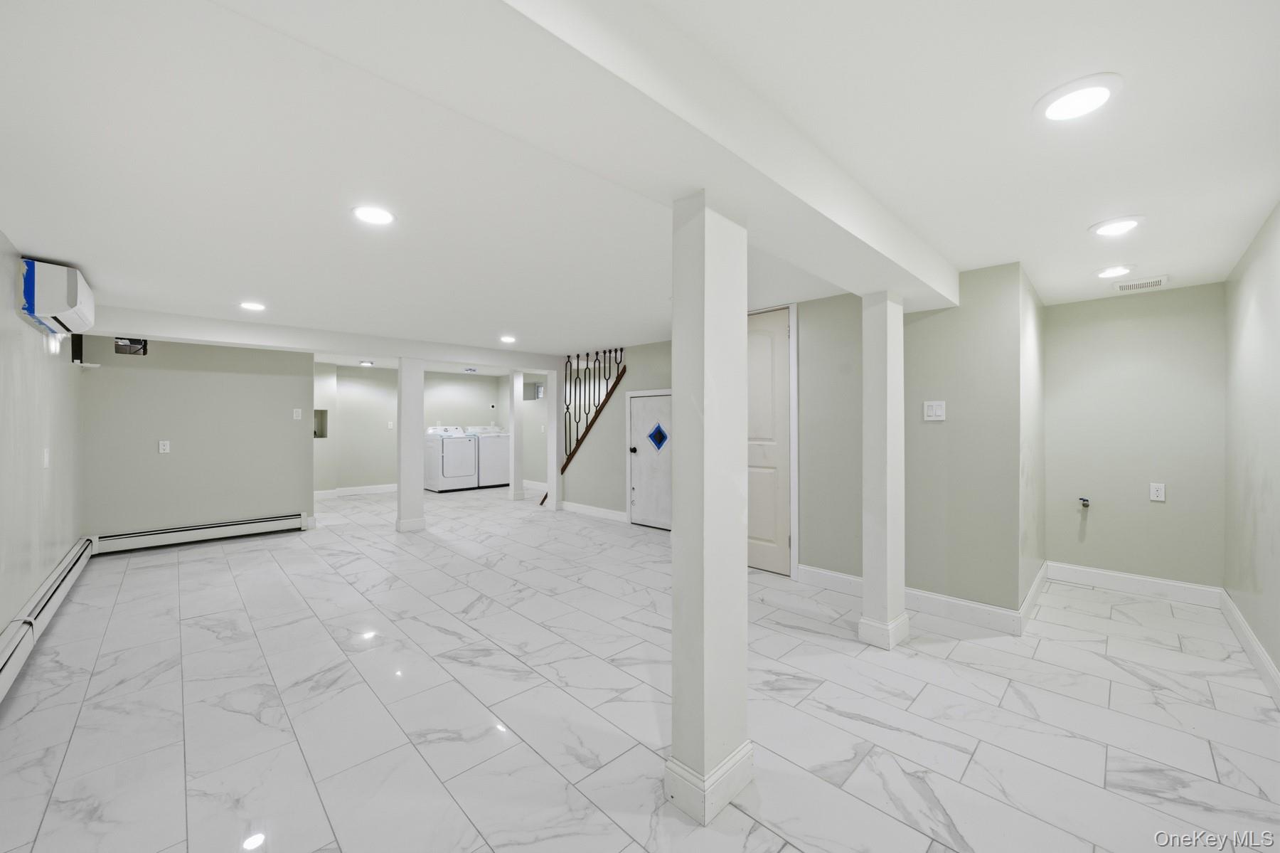 104-11 205th Street Queens, NY 11412 - Photo 38 of 50 Finished basement with light marble finish floors, stairway, recessed lighting, a baseboard heating unit, and washer and clothes dryer
