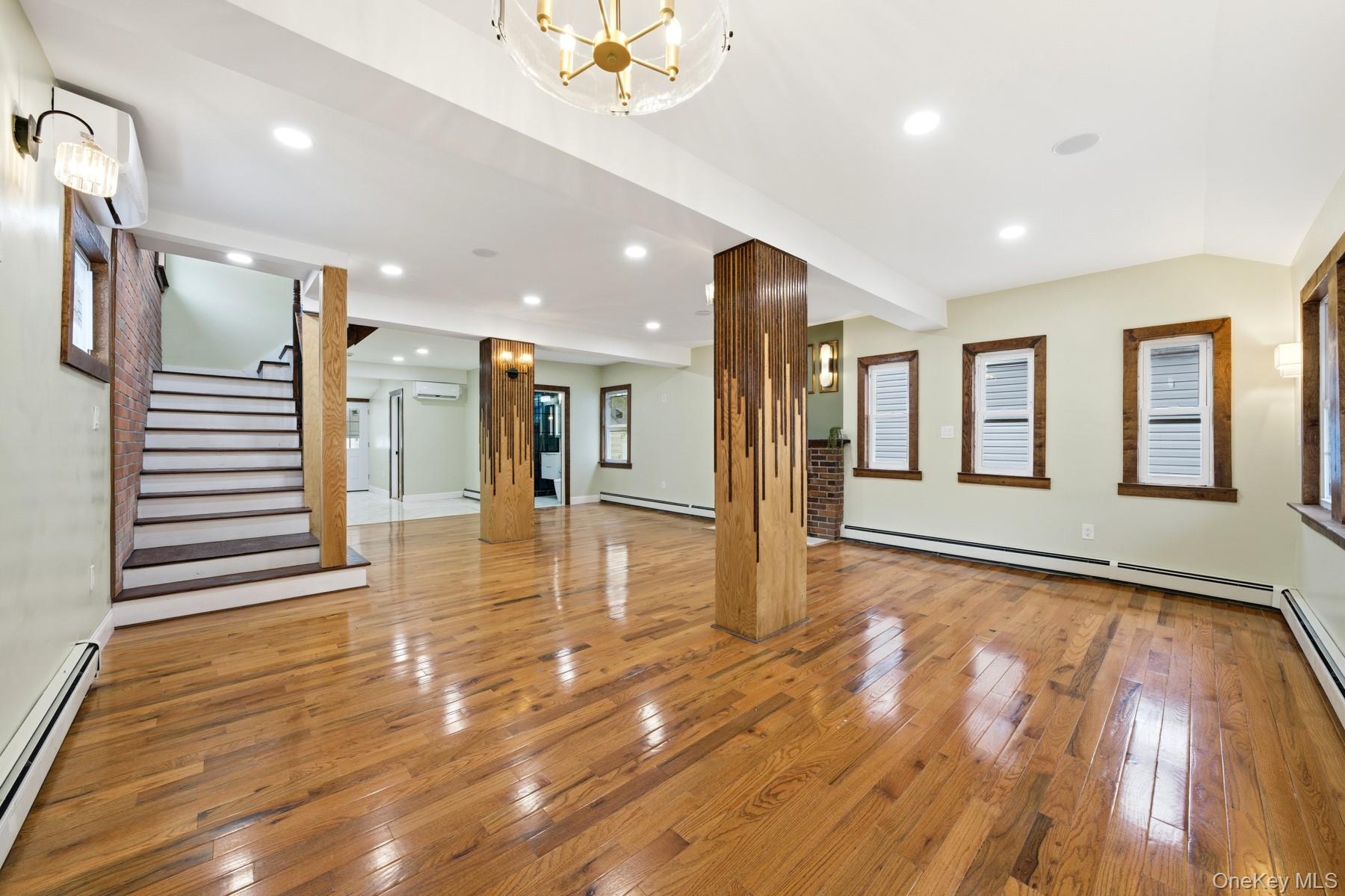 104-11 205th Street Queens, NY 11412 - Photo 4 of 50 Unfurnished living room with stairway, light wood-type flooring, a baseboard heating unit, a chandelier, and recessed lighting