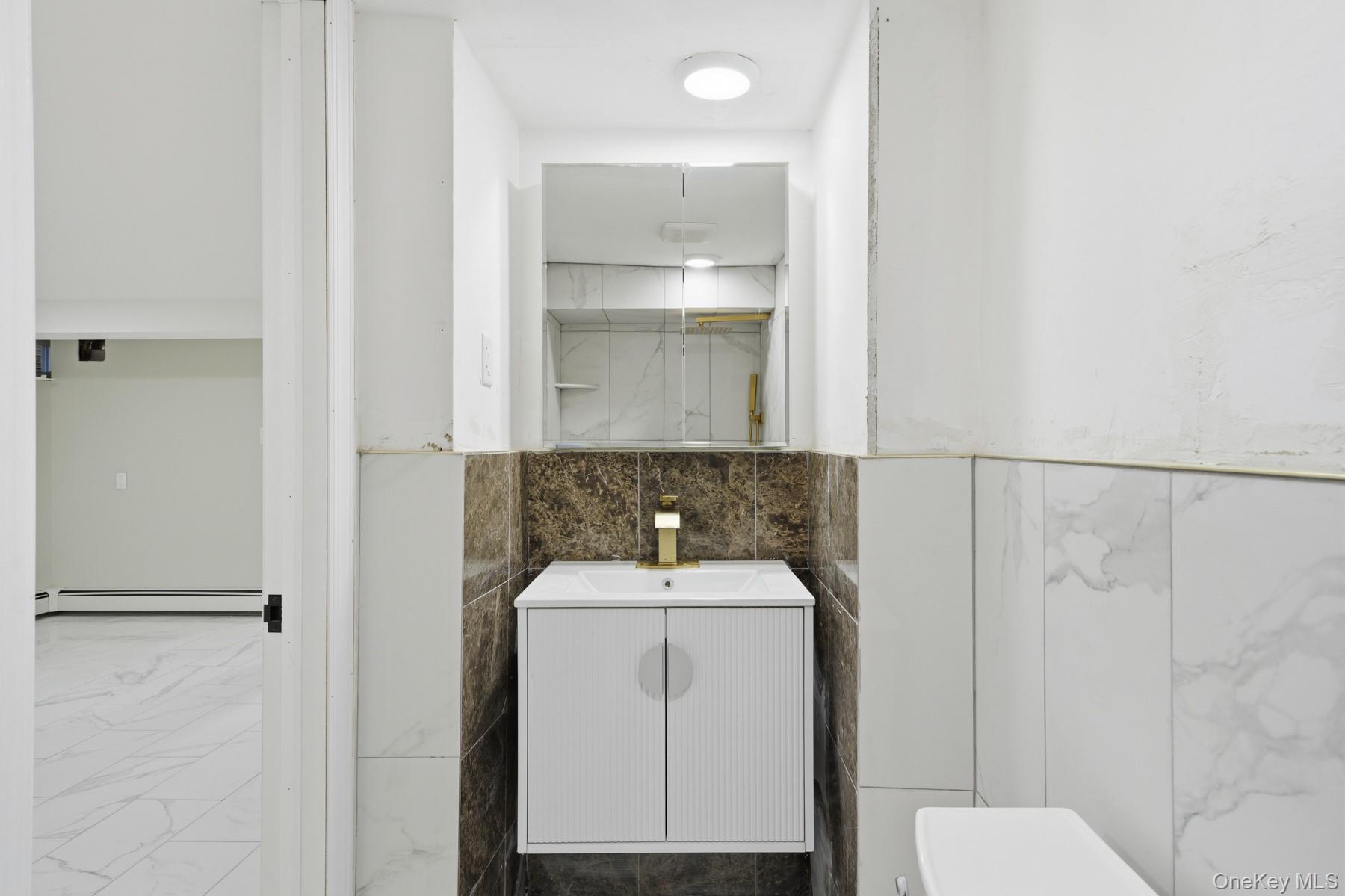 104-11 205th Street Queens, NY 11412 - Photo 42 of 50 Bathroom featuring vanity, tile walls, and a baseboard heating unit