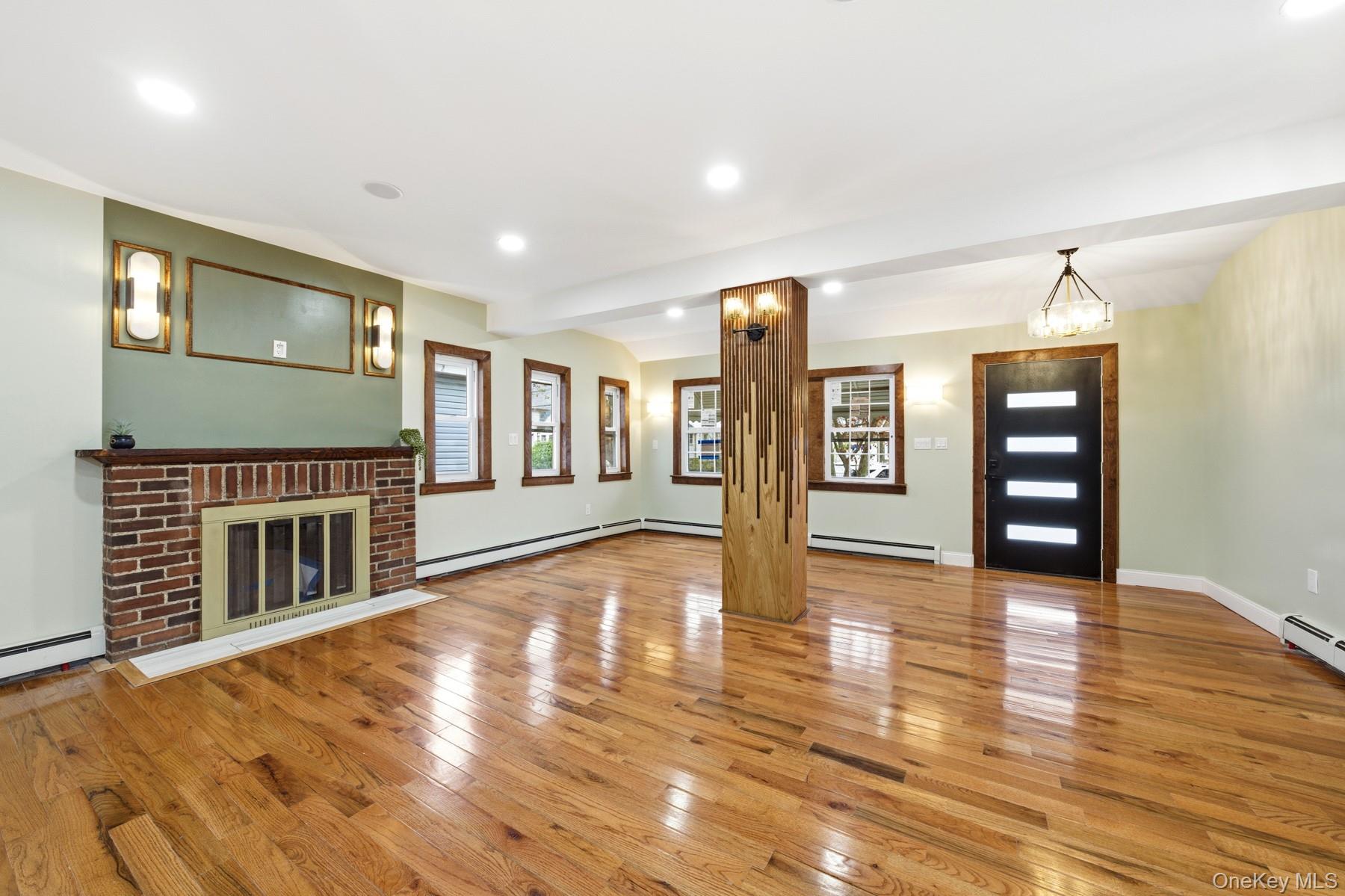 104-11 205th Street Queens, NY 11412 - Photo 8 of 50 Unfurnished living room featuring healthy amount of natural light, light wood-style flooring, recessed lighting, a brick fireplace, and beamed ceiling