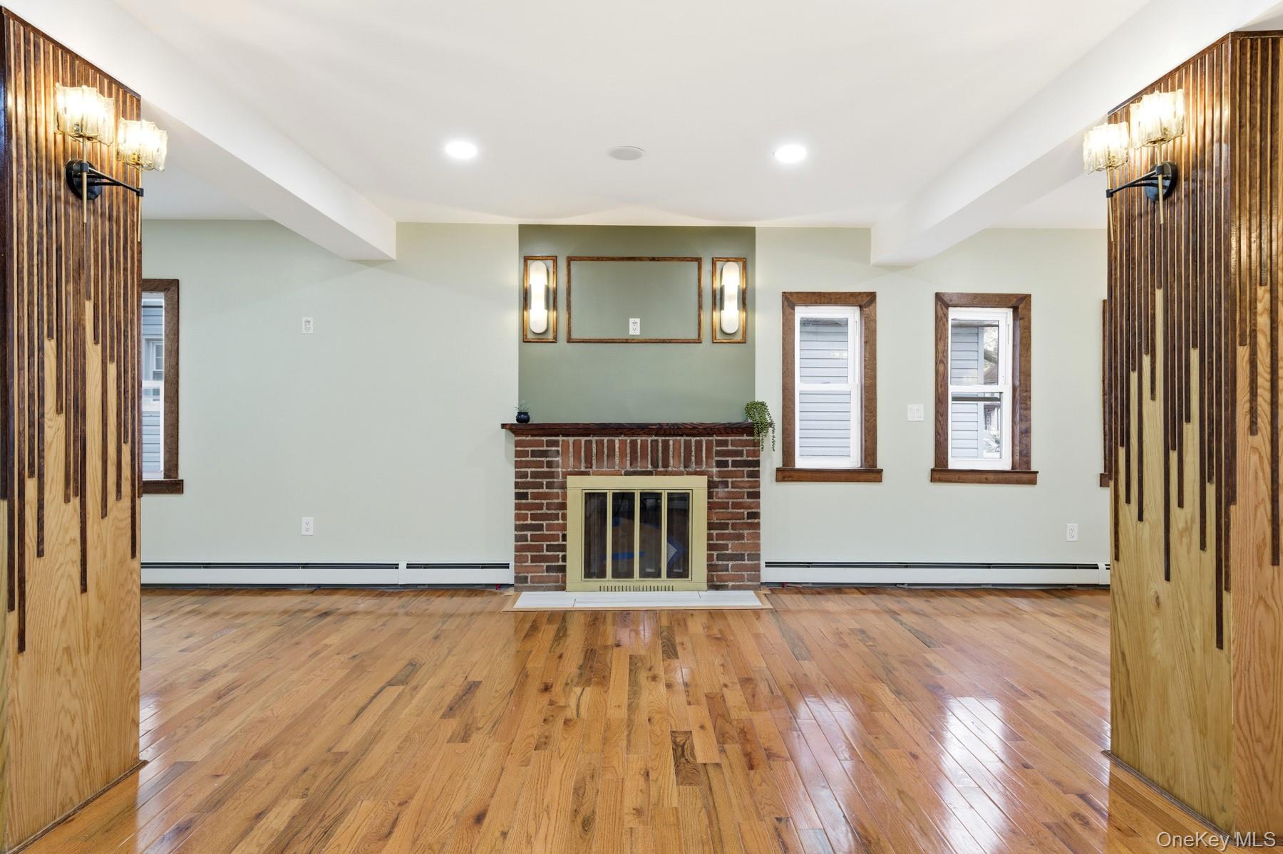104-11 205th Street Queens, NY 11412 - Photo 9 of 50 Unfurnished living room with light wood-type flooring, recessed lighting, a fireplace, and a baseboard radiator