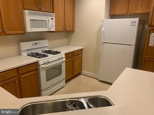 a kitchen with granite countertop a sink stove and refrigerator