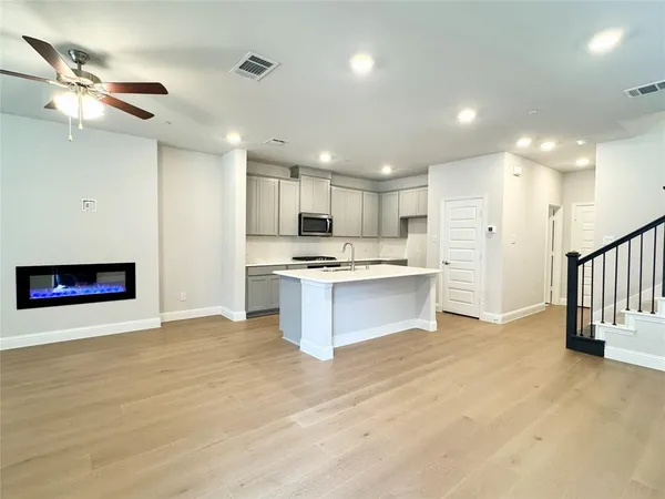 a large kitchen with stainless steel appliances kitchen island granite countertop a stove a sink and a refrigerator with wooden floor