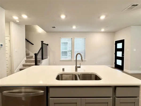 a kitchen with stainless steel appliances granite countertop a stove top oven a sink dishwasher and a refrigerator with wooden floor