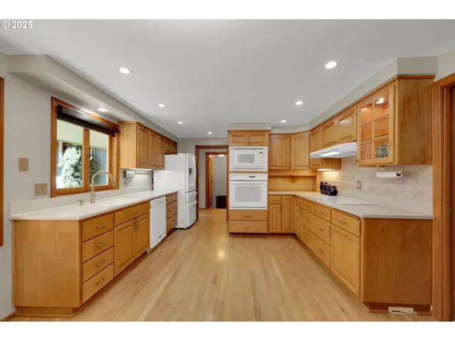 a large kitchen with stainless steel appliances a large counter top a stove a sink dishwasher and a refrigerator