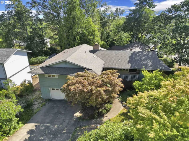 an aerial view of a house with a yard and trees all around
