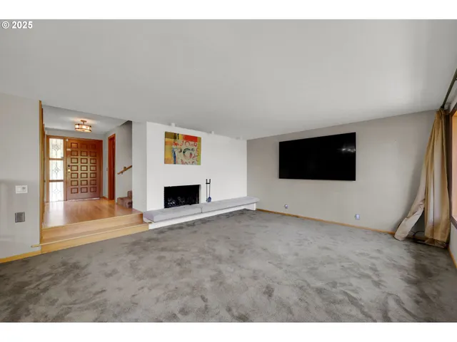 a view of an empty room with a fireplace and wooden floor