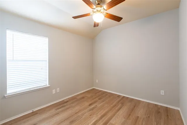 an empty room with a window and a fan