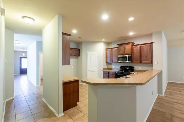 a kitchen with stainless steel appliances granite countertop a refrigerator a sink a stove top oven and a refrigerator
