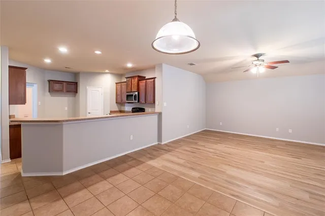 an empty room with wooden floor fan and windows