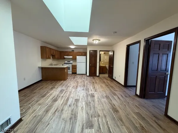 a view of empty room with wooden floor and window