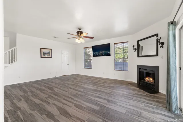 a view of empty room with wooden floor and fireplace