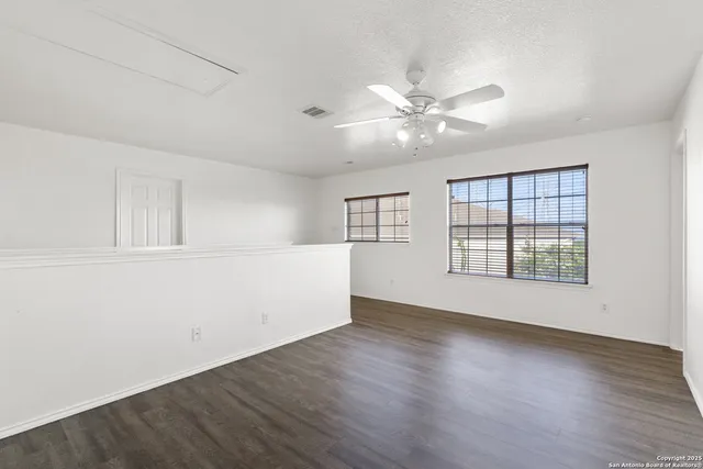 a view of empty room with wooden floor and fan