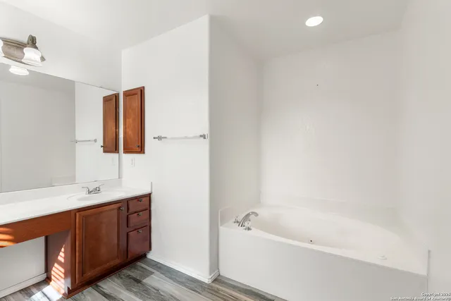 a bathroom with a tub sink and mirror