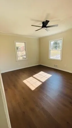 an empty room with wooden floor and windows