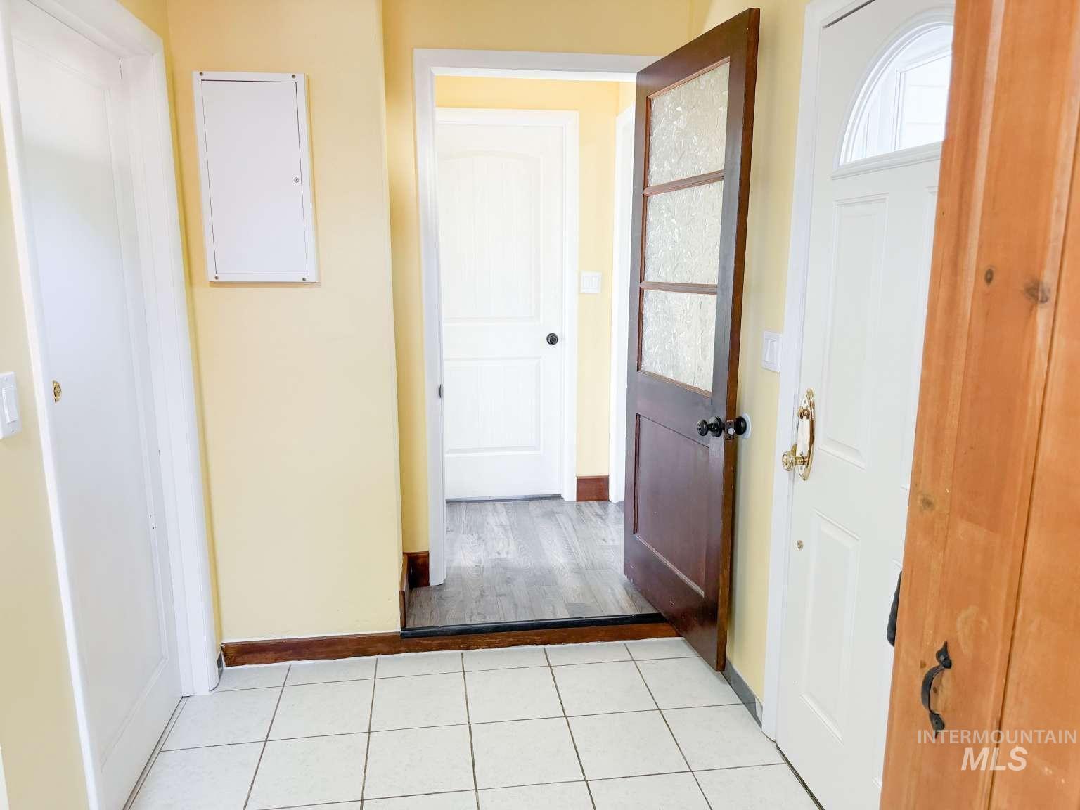 1158 South Powerline Road Nampa, ID 83686 - Photo 23 of 46 Entryway featuring white square floor tiles, light yellow walls, and a white paneled door with an arched transom window
