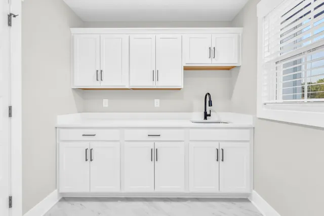 a kitchen with white cabinets and sink