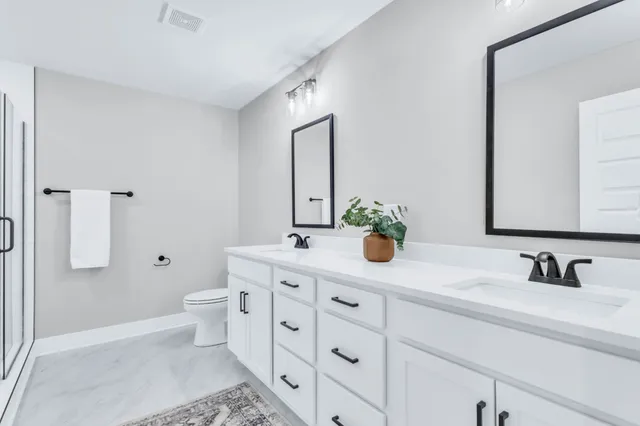 a bathroom with a double vanity sink toilet and mirror