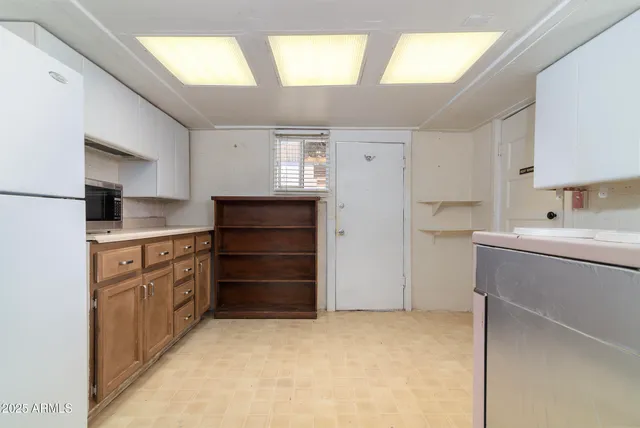 a kitchen with a refrigerator and white cabinets