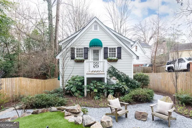 a view of a white house with a yard covered in forest