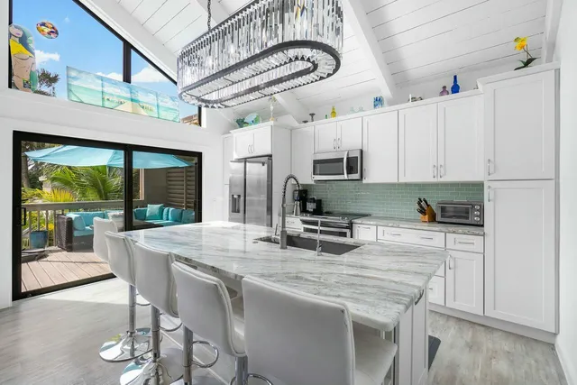 a kitchen with stainless steel appliances granite countertop a stove a refrigerator a kitchen island with white cabinets and wooden floor