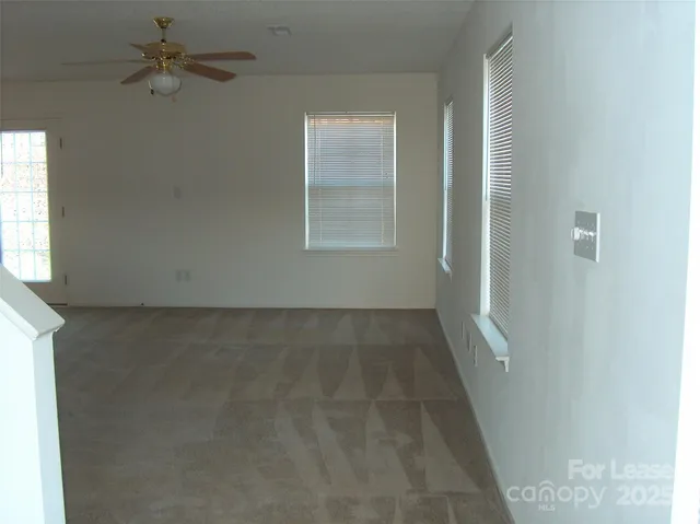 an empty room with a window and a ceiling fan