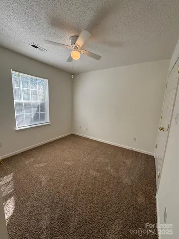 an empty room with windows and fan