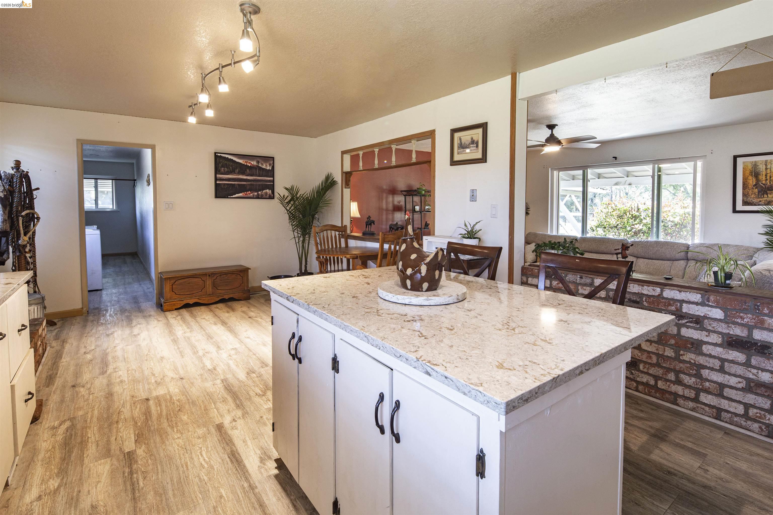 10458 Southworth Road Valley Springs, CA 95252 - Photo 10 of 24 Kitchen with a center island, light wood-type flooring, a textured ceiling, light stone counters, and white cabinets