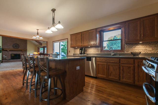 3087 Wagner Road Aurora, IL 60502 - Photo 5 of 20 a kitchen with stainless steel appliances granite countertop wooden floors stove top oven with a dining table and chairs