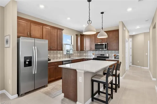 a kitchen with stainless steel appliances granite countertop a refrigerator a sink a stove a microwave a island with a refrigerator